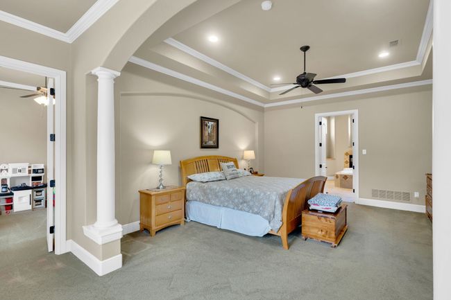 Bedroom featuring decorative columns, carpet floors, ornamental molding, a raised ceiling, and arched walkways | Image 20