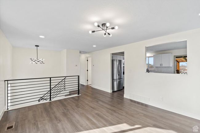 Empty room with visible vents, baseboards, a chandelier, and wood finished floors | Image 6
