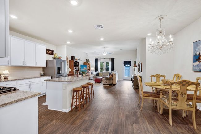 Kitchen featuring visible vents, white cabinets, open floor plan, dark wood-type flooring, and high end refrigerator | Image 10