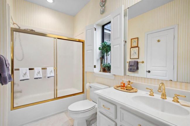 This delightful full bath services the secondary bedroom and second floor living areas. Soft and delicately striped wallpaper adds appeal. The glass shower enclosure sits atop a cast iron bathtub. | Image 32