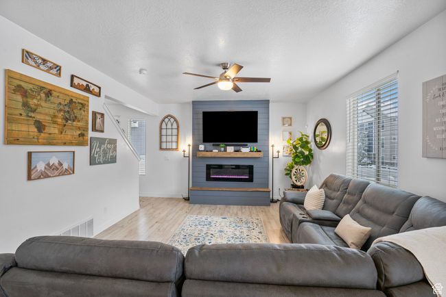 Living area with visible vents, baseboards, a fireplace, light wood-style flooring, and ceiling fan | Image 26