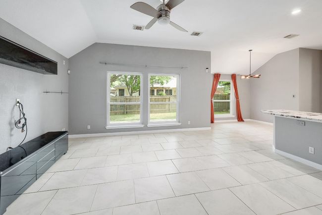 Unfurnished living room featuring visible vents, ceiling fan with notable chandelier, and lofted ceiling | Image 5