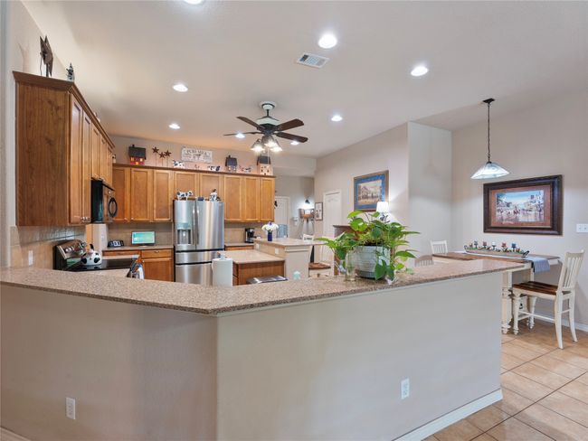 Kitchen featuring stainless steel appliances, ceiling fan, light tile patterned floors, a center island, and recessed lighting | Image 8