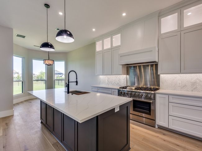 Kitchen featuring high end stainless steel range, a sink, a kitchen island with sink, decorative backsplash, and recessed lighting | Image 25