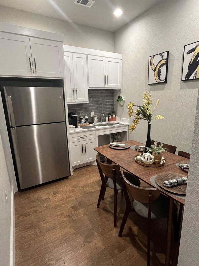 Kitchen featuring freestanding refrigerator, tasteful backsplash, light countertops, white cabinets, and wood finished floors | Image 14
