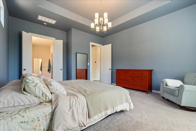 Bedroom featuring a chandelier, light colored carpet, baseboards, and visible vents | Image 18