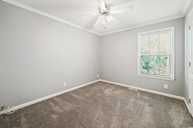 Carpeted empty room featuring ceiling fan, crown molding, and baseboards | Image 25