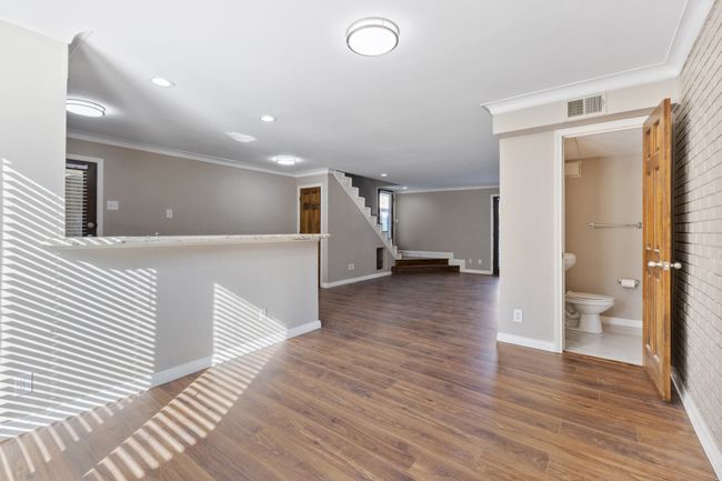 Empty room with crown molding, visible vents, baseboards, and wood finished floors | Image 11