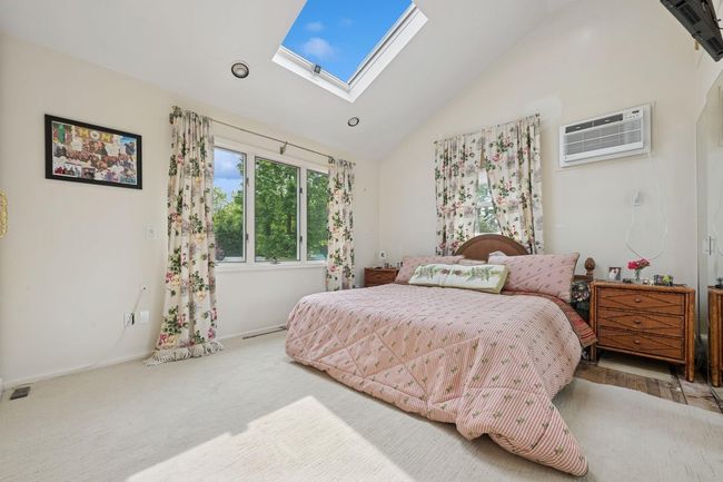 Bedroom with a wall mounted AC, a skylight, baseboards, carpet, and high vaulted ceiling | Image 19