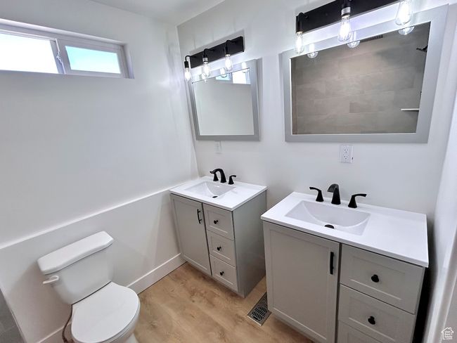 Bathroom with two vanities, wood finished floors, toilet, and a sink | Image 20