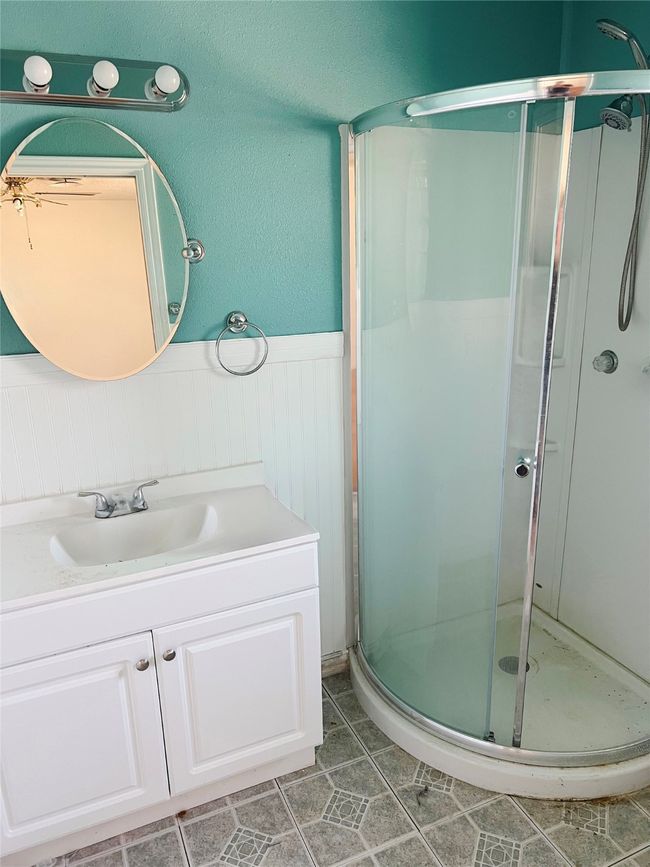 Bathroom with a wainscoted wall, a stall shower, tile patterned flooring, and vanity | Image 10