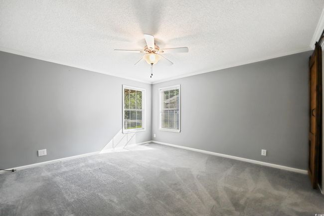 Carpeted spare room featuring ceiling fan, baseboards, a textured ceiling, and ornamental molding | Image 18