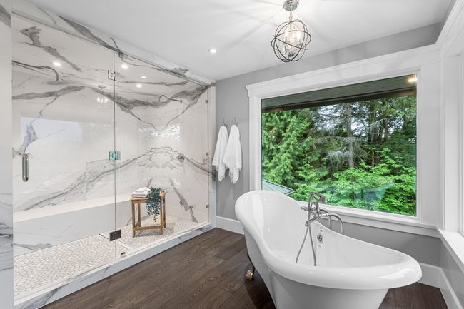Bathroom featuring a soaking tub, a marble finish shower, wood finished floors, a chandelier, and recessed lighting | Image 23
