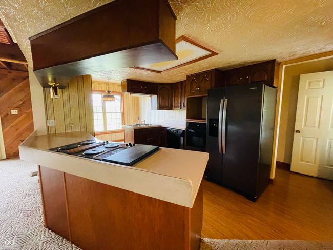 kitchen featuring black appliances, a sink, light countertops, dark brown cabinetry, and wood finished floors | Image 5