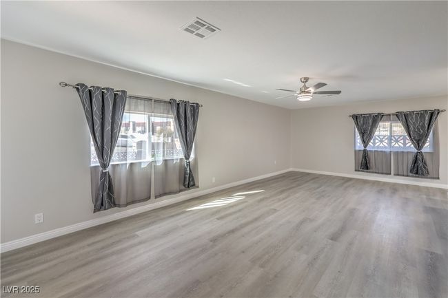 Unfurnished room with a ceiling fan, wood finished floors, visible vents, and baseboards | Image 7