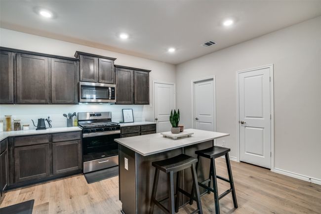 Kitchen featuring appliances with stainless steel finishes, light wood-style floors, light countertops, a kitchen breakfast bar, and a center island | Image 10