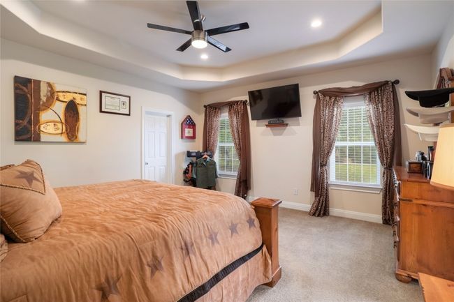 A beautiful primary bedroom with tall ceiling, trey ceiling, all the while gazing into the backyard. | Image 16