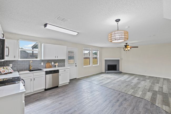 Kitchen featuring stainless steel appliances, a ceiling fan, light wood-type flooring, and a textured ceiling | Image 9