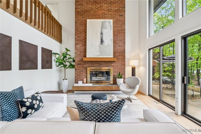 Living area featuring wood finished floors, a brick fireplace, and a towering ceiling | Image 18