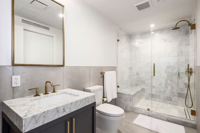 Bathroom with tile walls, visible vents, toilet, and a stall shower | Image 12