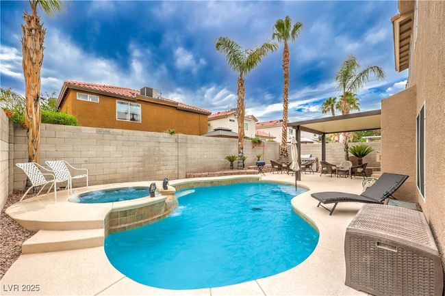 View of swimming pool with a patio area, a fenced backyard, and a pool with connected hot tub | Image 32