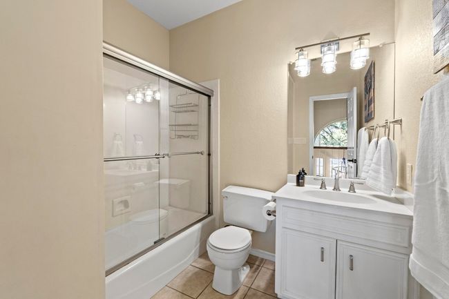 Full bath with tile patterned flooring, toilet, vanity, and shower / bath combination with glass door | Image 26