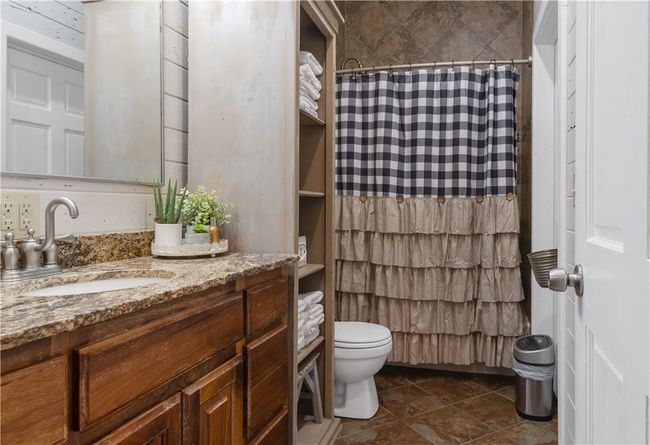 Bathroom with a shower with shower curtain, vanity, and toilet | Image 7