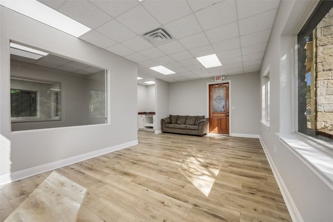 Unfurnished room featuring wood finished floors, visible vents, a drop ceiling, and baseboards | Image 9