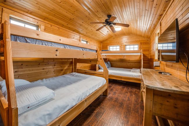Upstairs Bedroom featuring ceiling fan, wooden ceiling, dark hardwood / wood-style floors, lofted ceiling, and wooden walls | Image 6