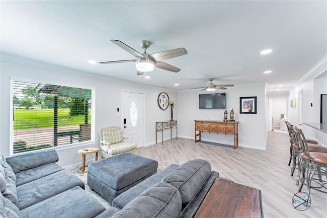 Living room featuring ceiling fan, ornamental molding, and light hardwood / wood-style flooring | Image 21