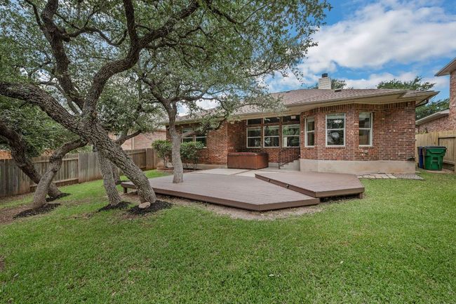 Step outside to your private backyard retreat with a covered patio, extended deck, mature trees, and lush landscaping. Unwind in the optional hot tub, perfect for Texas evenings. | Image 29