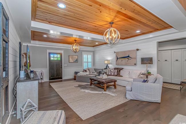Living room with a tray ceiling, a chandelier, wood ceiling, dark wood-style floors, and recessed lighting | Image 5