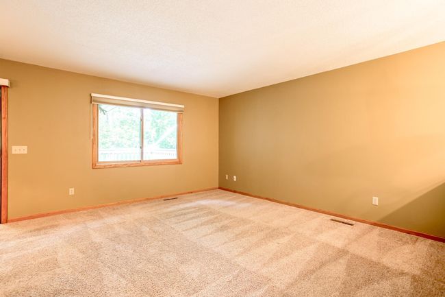 Bright and spacious living area with plush carpeting, large windows, and neutral tones—ready to accommodate your ideal setup. | Image 7