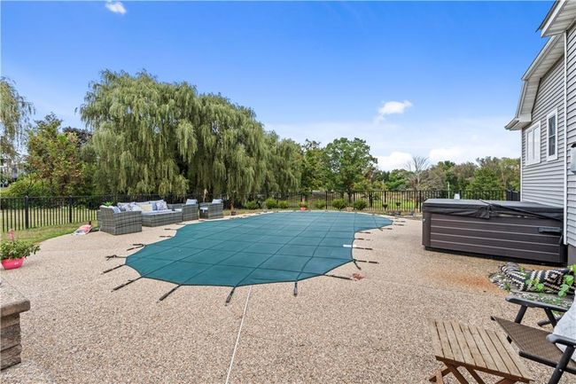 View of swimming pool with an outdoor living space, a patio area, a hot tub, and view of wooded area | Image 31