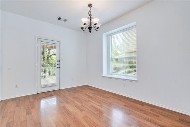 The dining area features a chandelier and faces the back door that opens to the covered patio and backyard, perfect for indoor-outdoor entertaining. | Image 6