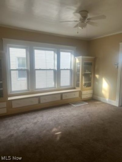 Carpeted empty room with ceiling fan and crown molding | Image 3