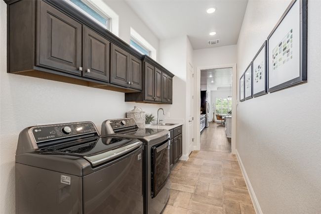 Laundry room with washer and clothes dryer, light stone finish floors, cabinet space, and recessed lighting | Image 31