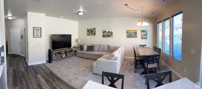 Living area featuring an inviting chandelier, a textured ceiling, dark wood-style floors, and baseboards | Image 12
