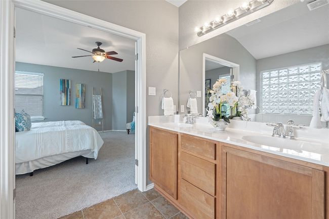 Ensuite bathroom featuring double vanity, a ceiling fan, tile patterned floors, and a tub to relax in | Image 28