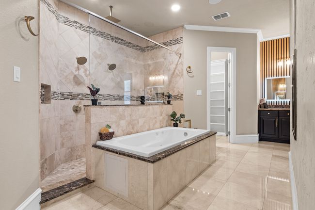 Full bathroom featuring a walk in shower, ornamental molding, a garden tub, vanity, and a walk in closet | Image 17