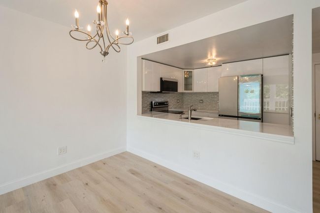 Kitchen featuring freestanding refrigerator, stainless steel electric stove, light wood-style floors, white cabinets, and a chandelier | Image 5