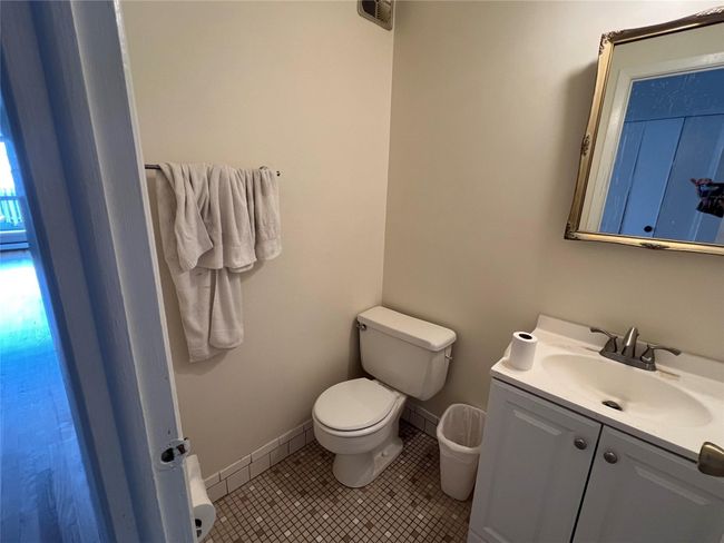 Half bath featuring toilet, vanity, tile patterned flooring, and baseboards | Image 7