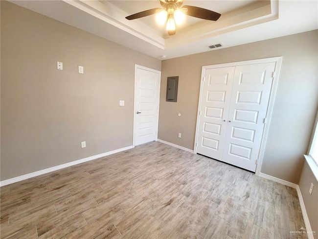 Unfurnished bedroom with a raised ceiling, electric panel, light wood-type flooring, and a closet | Image 14