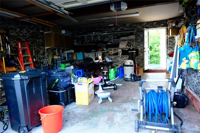 Garage featuring a garage door opener and a workshop area, also entire to the backyard and separate entry to frist floor living room | Image 23