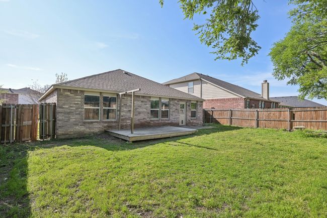 Rear view of property featuring a fenced backyard, a deck, brick siding, roof with shingles, and a lawn | Image 32