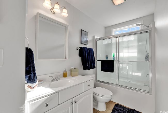 Full bathroom featuring toilet, tile patterned floors, bath / shower combo with glass door, and vanity | Image 27