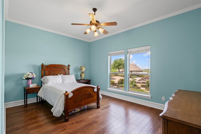 Bedroom with a tray ceiling, dark wood-style flooring, ornamental molding, and visible vents | Image 29