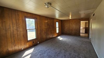 Unfurnished room featuring dark carpet and wooden walls | Image 1