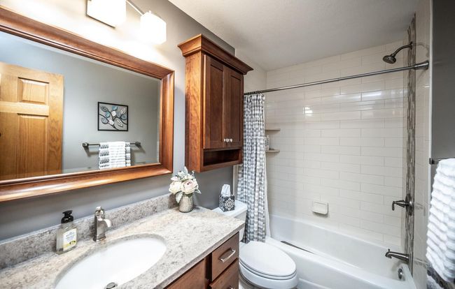 Updated upper full bath has COREtec LVT flooring, higher vanity upgraded with dovetail drawer construction & soft close, tub & shower with tile surround, solar tube for additional brightness, quartz countertop & custom mirror & large medicine cabinet | Image 21