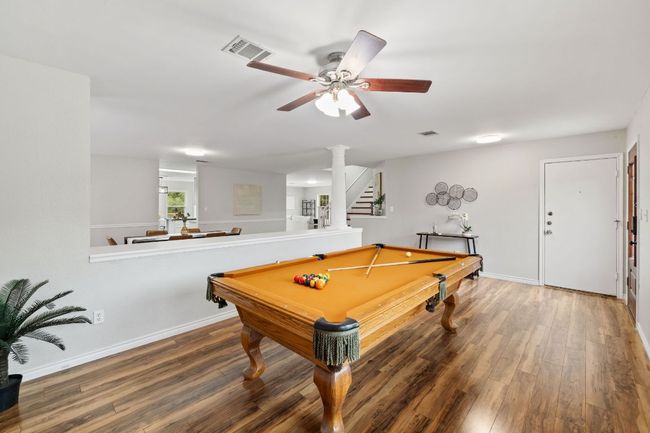Recreation room with wood finished floors, ceiling fan, decorative columns, baseboards, and billiards table | Image 6